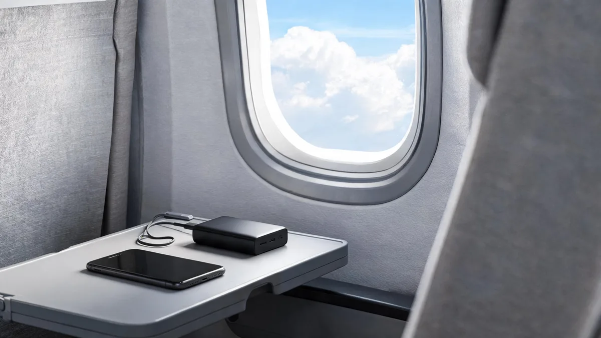 飛行機内のトレイテーブルに置かれたモバイルバッテリーとスマートフォン